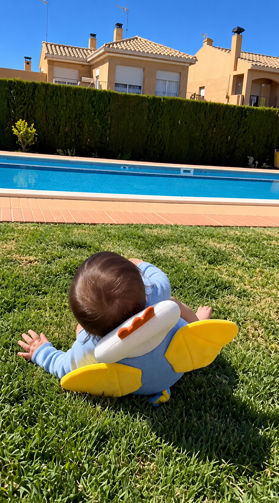Baby on the grass wearing a plush backpack